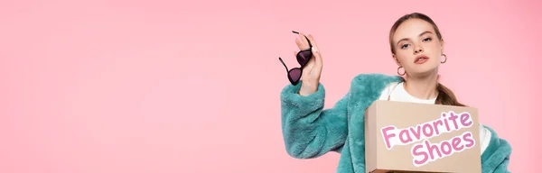 Panoramic crop of woman holding sunglasses and box with favorite shoes lettering isolated on pink, black friday concept — Stock Photo