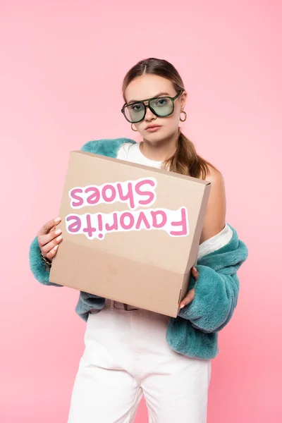 Giovane donna in occhiali da sole in possesso di scatola con scarpe preferite lettering su rosa, concetto di venerdì nero — Foto stock