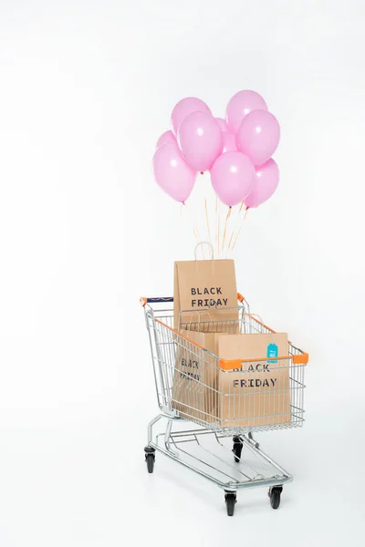Borse shopping con scritta venerdì nero nel carrello con palloncini su bianco — Foto stock