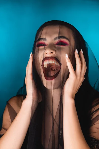 Mariée maléfique avec maquillage noir et voile riant sur bleu — Photo de stock