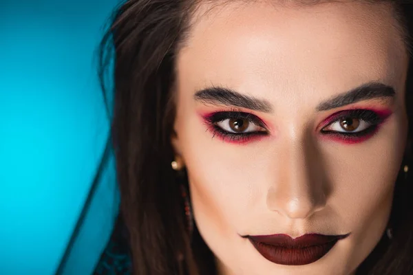 Close up of woman with black makeup looking at camera on blue — Stock Photo