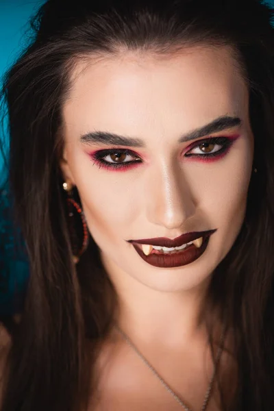 Vampir mit schwarzem Make-up und weißen Gruselzähnen blickt in die Kamera — Stockfoto