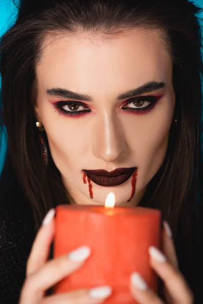 Селективный фокус женщины с кровью на лице, держащей горящую свечу — стоковое фото