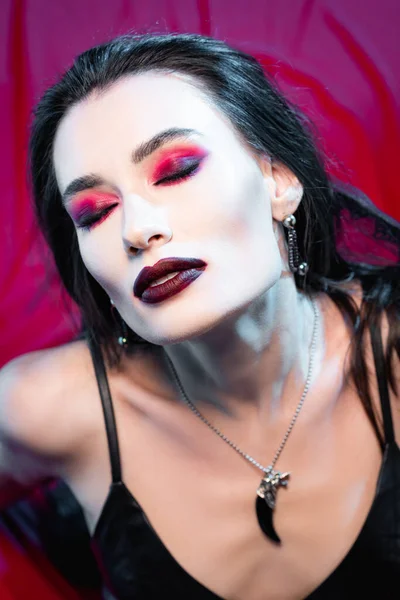 High angle view of pale and young woman with closed eyes on red — Stock Photo