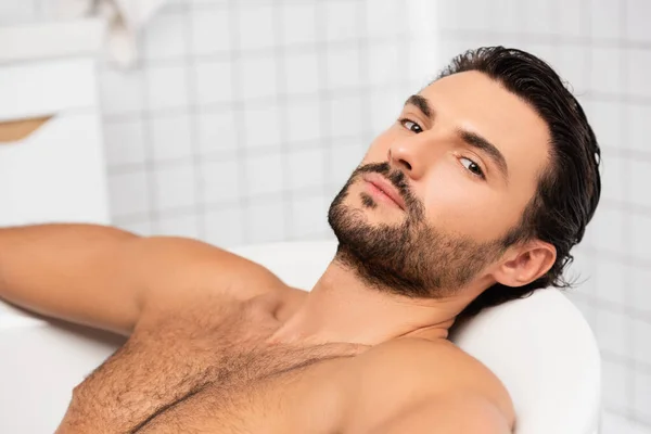 Barbudo hombre mirando a la cámara mientras toma el baño - foto de stock