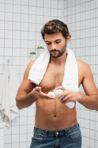 Uomo muscolare con asciugamano intorno al collo spremitura schiuma da barba — Foto stock