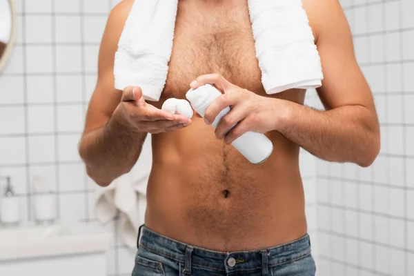 Vista recortada del hombre sin camisa con toalla exprimiendo espuma de afeitar en el baño - foto de stock