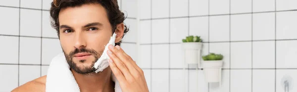 Homem barbudo aplicando espuma de barbear no banheiro, banner — Fotografia de Stock