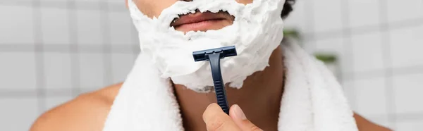 Cropped view of man with shaving foam on face holding disposable razor, banner — Stock Photo