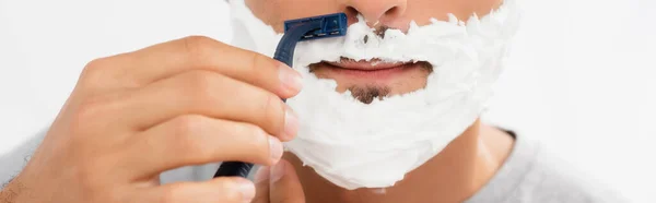 Vista recortada del hombre con espuma en el afeitado facial con afeitadora aislada en gris, pancarta - foto de stock