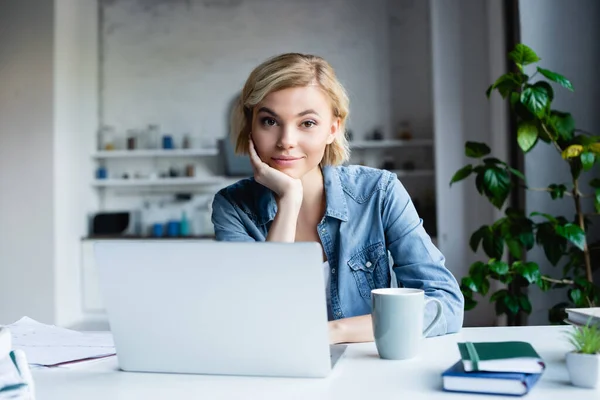 Junge blonde Frau arbeitet von zu Hause aus mit Laptop — Stockfoto