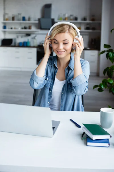 Jovem loira mulher colocando fones de ouvido e tendo webinar online — Fotografia de Stock