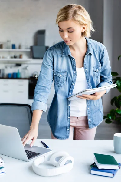 Joven rubia sosteniendo cuaderno y estudiando desde casa - foto de stock