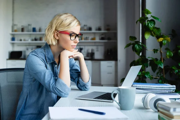 Young blonde woman in eyeglasses working from home — Stock Photo