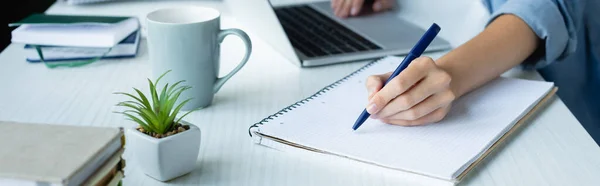 Cropped view of woman making notes in notebook, horizontal banner — Stock Photo