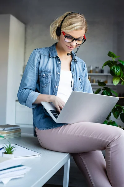 Giovane donna bionda in occhiali da vista digitando sul computer portatile — Foto stock