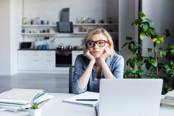 Bouleversé femme blonde dans les lunettes d'étude de la maison — Photo de stock