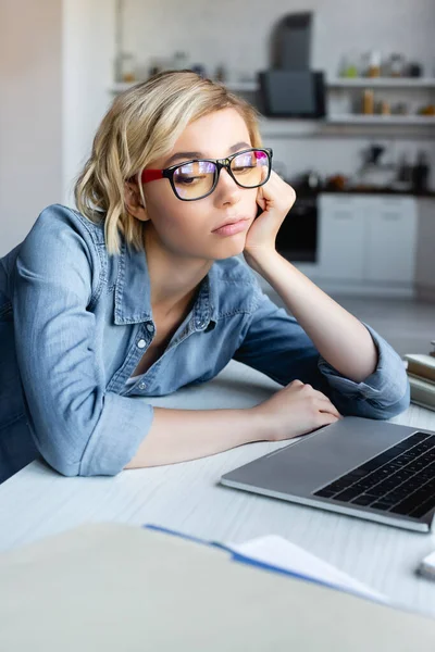 Mujer rubia disgustada en gafas que trabajan desde casa - foto de stock