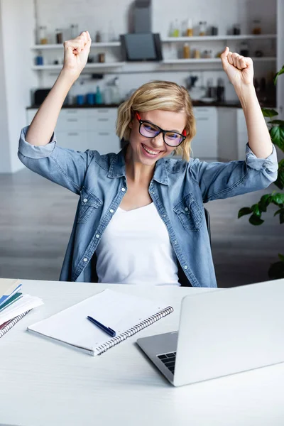 Joven rubia en gafas feliz con las manos levantadas - foto de stock