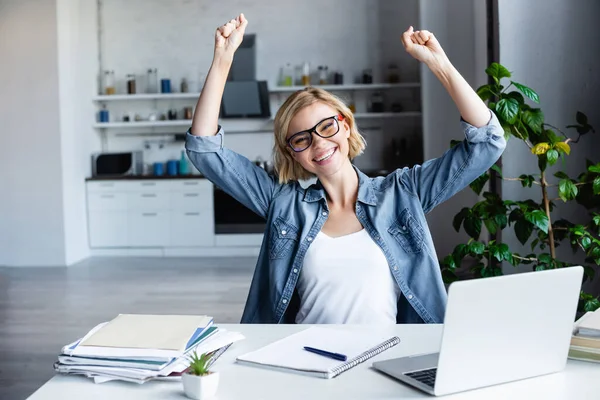 Joven rubia en gafas feliz con las manos levantadas - foto de stock