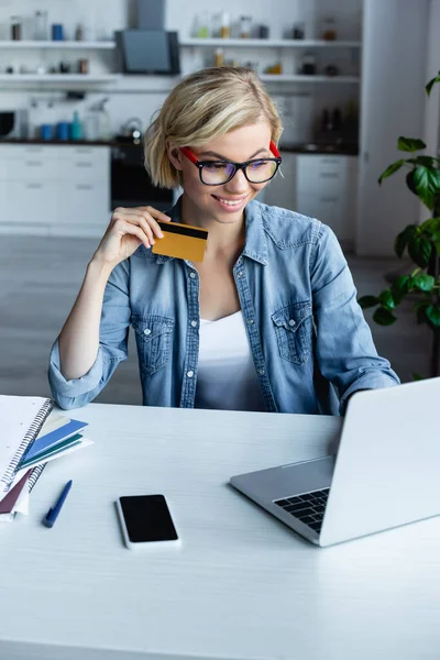 Young blonde woman in eyeglasses making purchase online — Stock Photo