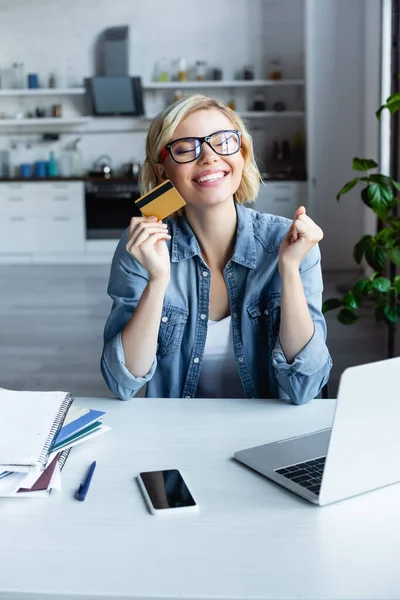 Mujer rubia feliz en gafas haciendo compra en línea - foto de stock