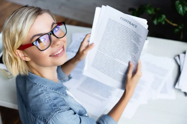 High angle view of young blonde woman in eyeglasses holding contract — Stock Photo