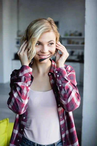 Young blonde woman in checkered shirt putting on headphones — Stock Photo
