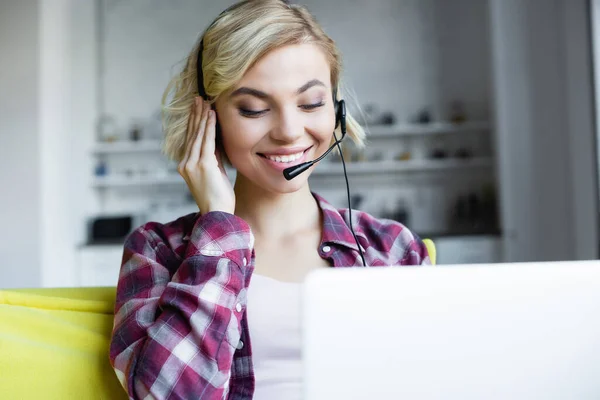 Sorrindo mulher loira em camisa quadriculada e fones de ouvido tendo conferência online — Fotografia de Stock