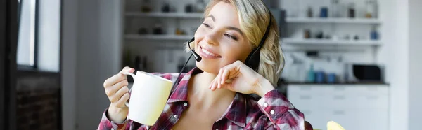 Jeune femme blonde en chemise à carreaux et écouteurs boire du thé, bannière — Photo de stock