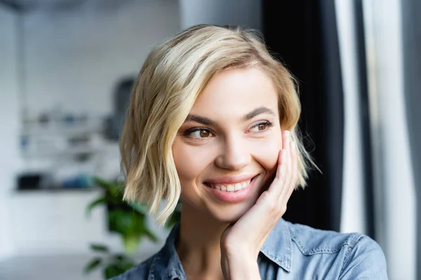 Retrato de mujer rubia sonriente mirando por la ventana - foto de stock