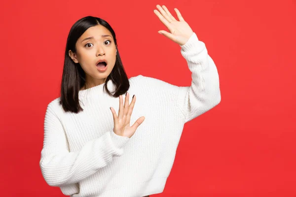 Shocked asian woman with open mouth showing stop sign with hands isolated on red — Stock Photo