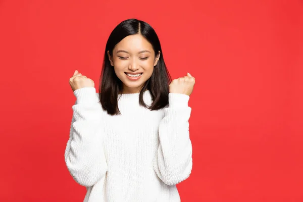 Junge asiatische Frau mit geschlossenen Augen jubelt und lächelt isoliert auf rot — Stockfoto