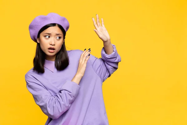 Asian woman in beret showing no gesture with hands isolated on yellow — Stock Photo