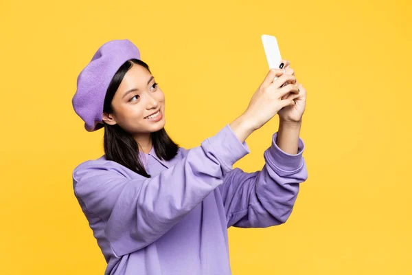 Feliz asiático mulher no boina tomando selfie no smartphone isolado no amarelo — Fotografia de Stock