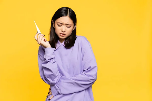 Malade asiatique femme tenant numérique thermomètre isolé sur jaune — Photo de stock