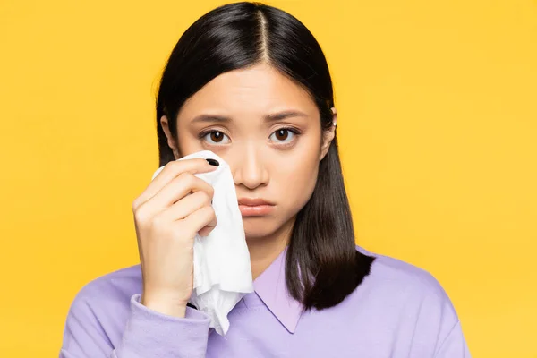 Triste asiático mulher segurando guardanapo enquanto chorando isolado no amarelo — Fotografia de Stock