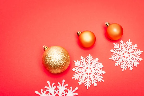 Top view of snowflakes, baubles on red background — Stock Photo