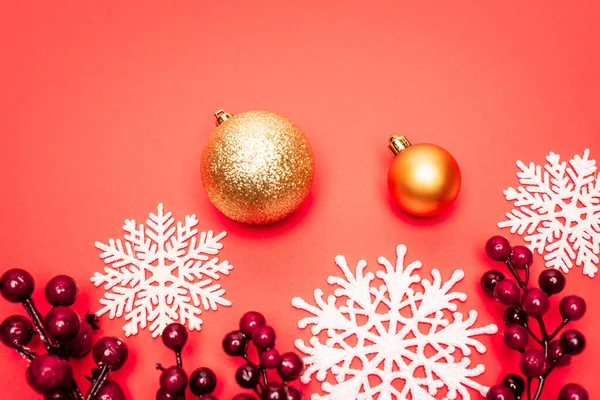 Draufsicht auf Kugeln, Schneeflocken und Beeren auf rotem Hintergrund — Stockfoto