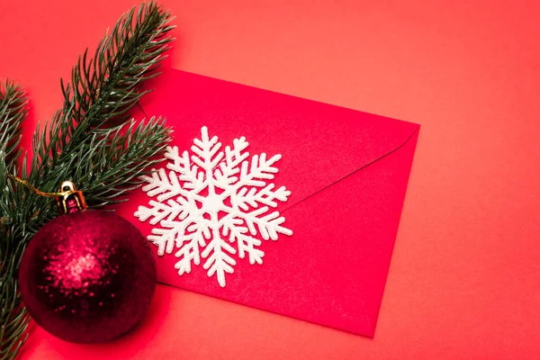 Вид зверху на різдвяну прикрасу та конверт на червоному тлі — Stock Photo