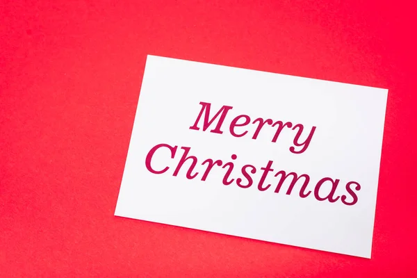 Top view of white merry Christmas card on red background — Stock Photo