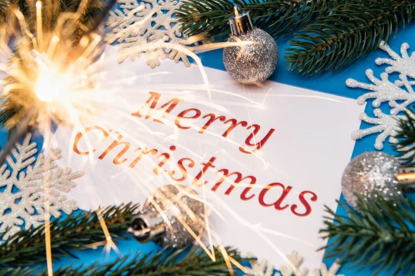 Frohe Weihnachten Karte, Dekoration und Wunderkerze auf blauem Hintergrund — Stockfoto