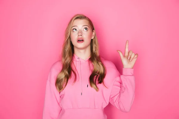 Pensive beautiful woman pointing up on pink background — Stock Photo