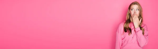 Scioccato bella donna che copre la bocca su sfondo rosa, banner — Foto stock