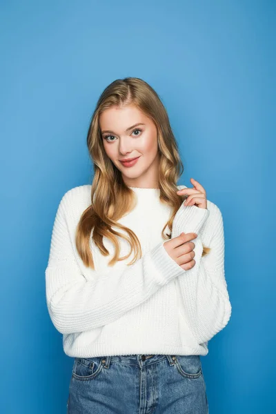 Pretty blonde beautiful woman in sweater isolated on blue — Stock Photo
