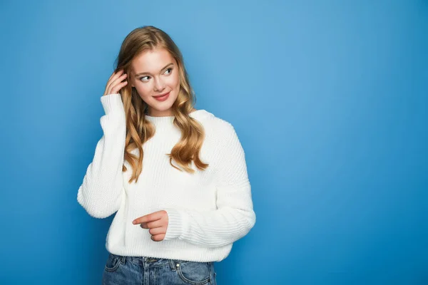 Blonde beautiful woman in sweater looking away isolated on blue background — Stock Photo