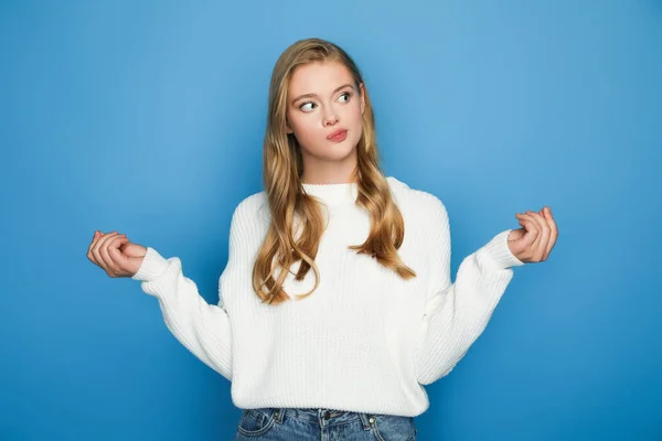 Thoughtful blonde beautiful woman in sweater isolated on blue background — Stock Photo