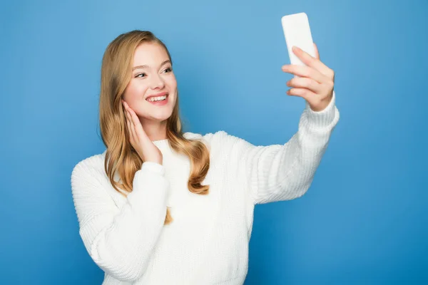 Sorridente bionda bella donna prendendo selfie isolato su sfondo blu — Foto stock
