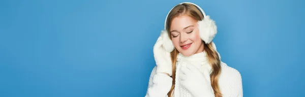 Lächelnde schöne Frau im winterweißen Outfit vereinzelt auf blauem Grund, Banner — Stockfoto