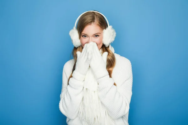 Усміхнена красива жінка в зимовому білому вбранні ізольована на синьому — стокове фото